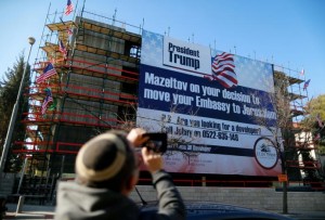 A man takes a picture of a giant banner on a building congratulating U.S. President-elect Donald Trump in Jerusalem, January 20, 2017 REUTERS/Ammar Awad/File Photo