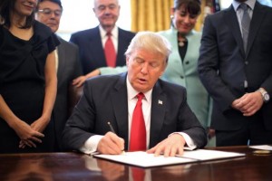 U.S. President Donald Trump signs an executive order cutting regulations, accompanied by small business leaders at the Oval Office of the White House in Washington U.S., January 30, 2017.  REUTERS/Carlos Barria