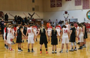 The Liberal MO Bulldogs girls basketball team holds hands to pray before tip-off with their opponents, the College Heights Cougars. 