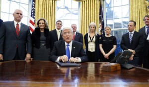 President Trump with Mike Pence far right with White House Staff signing executive orders on Saturday (AP Photo) 